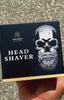 Man met een gladgeschoren hoofd en bril toont het resultaat van hoofdscheren met de Skull Master.